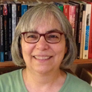 a woman in front of a bookcase in a green shirt