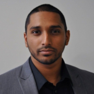 Mohamed in a gray suit jacket and dark shirt