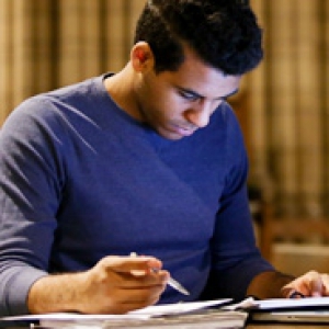 a man in a blue sweater looking at documents on a table