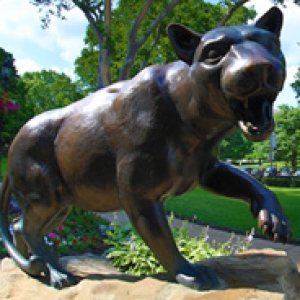 panther statue in front of a lush green background