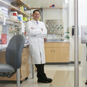 A man in a white lab coat standing in a lab