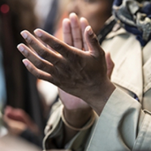 A person in a beige coat clapping