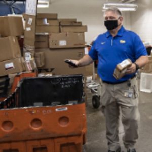 A Pitt staff member in a blue shirt in the mailroom