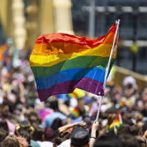 A pride march with a rainbow flag flying
