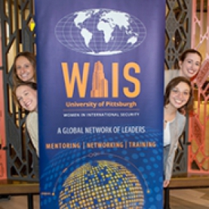 Four women pose next to a banner for Women in International Security
