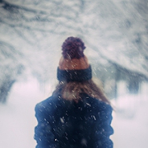 person wearing a stocking cap walking through snow