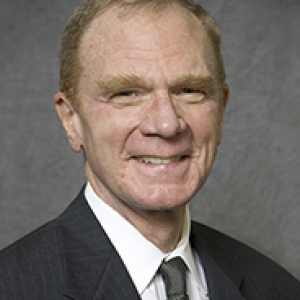 Braun in a suit in front of a gray background