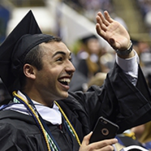 graduate in a cap and gown waving