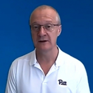 A man in a white golf shirt with a blue background