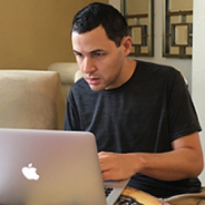 Man in a black shirt looking at a laptop