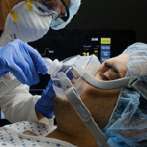 A physician adjusts a mask on a patient lying down