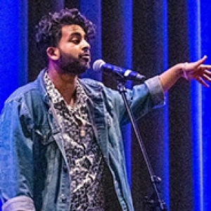 Rajamani on a stage with blue lights shining on him