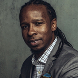 Ibram X. Kendi in a gray suit with his book