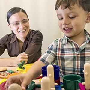 Libertus in a brown shirt and her 2-year-old Linus, playing with toys in a beige room