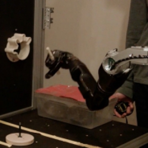 a black robotic arm lifting up a white cylinder