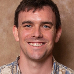 Logan Rice in a blue and brown shirt on a brown background