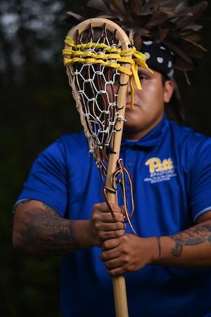 Man holding a wooden lacrosse stick