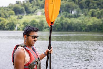 Man wearing life vest holds oars