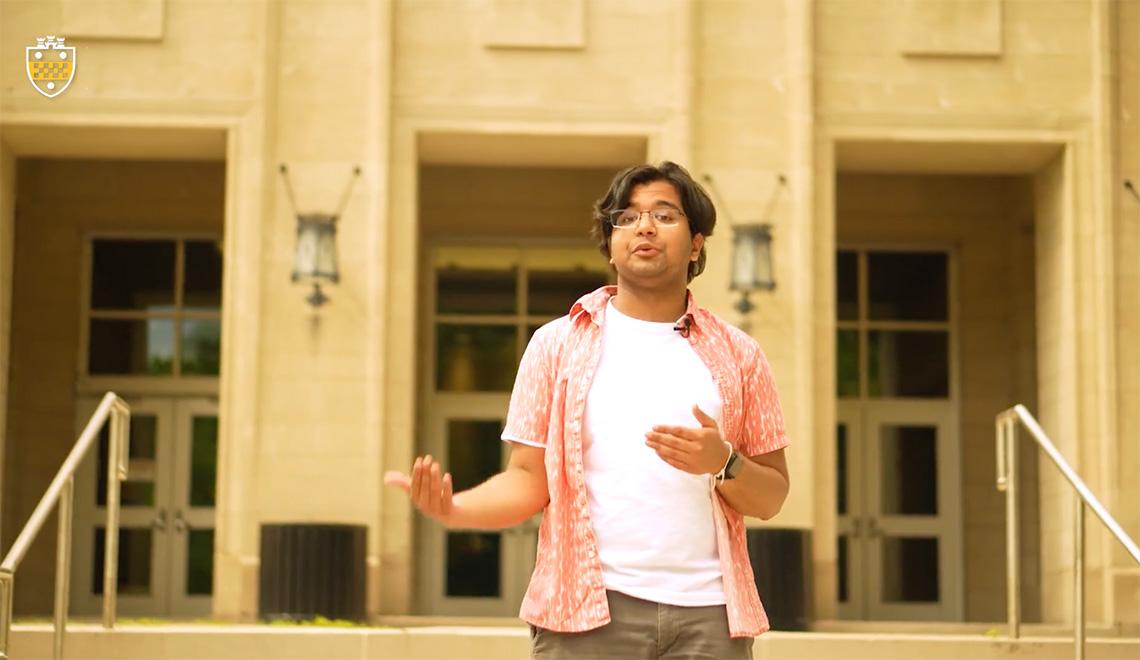 A still of Johnbosco speaking in front of a building