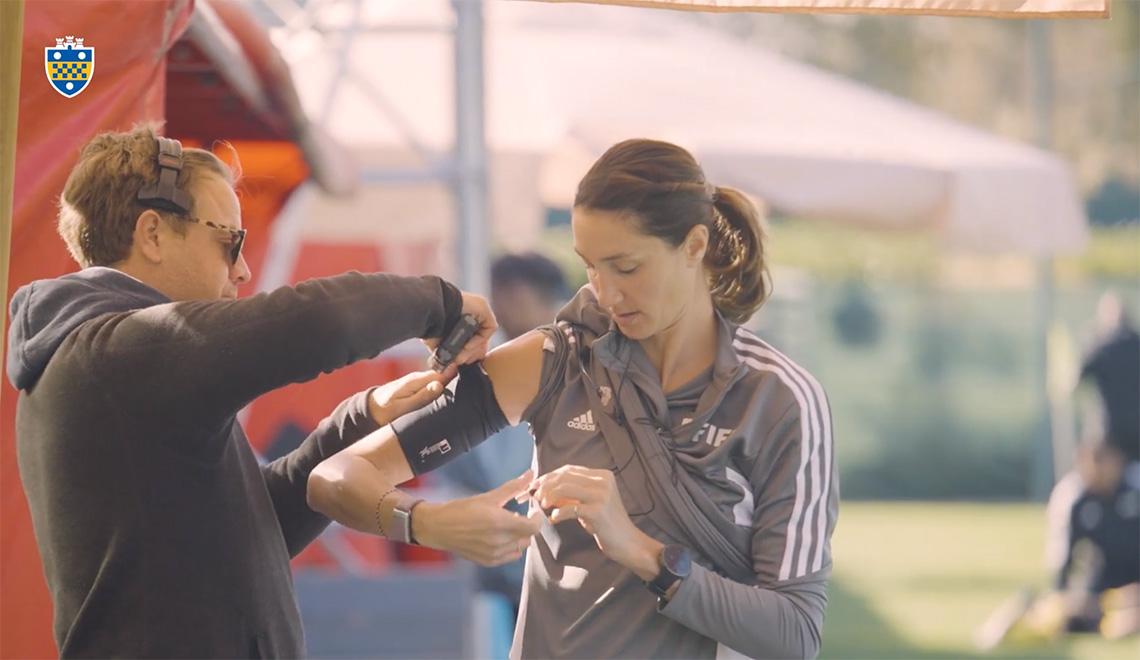 A person attaches an arm band to Nesbitt