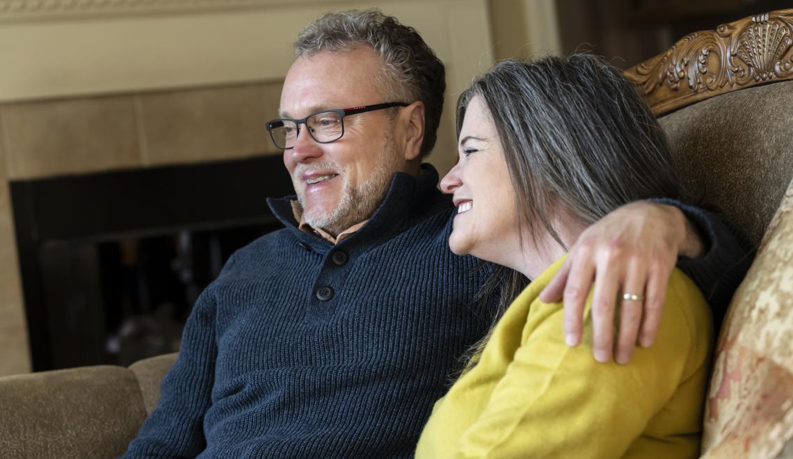 The Vorps sit on a couch in their home