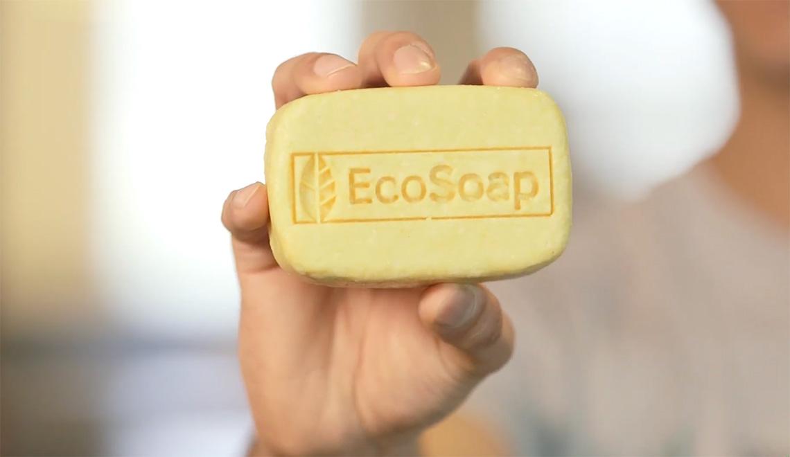 A hand holding up a bar of soap that reads EcoSoap