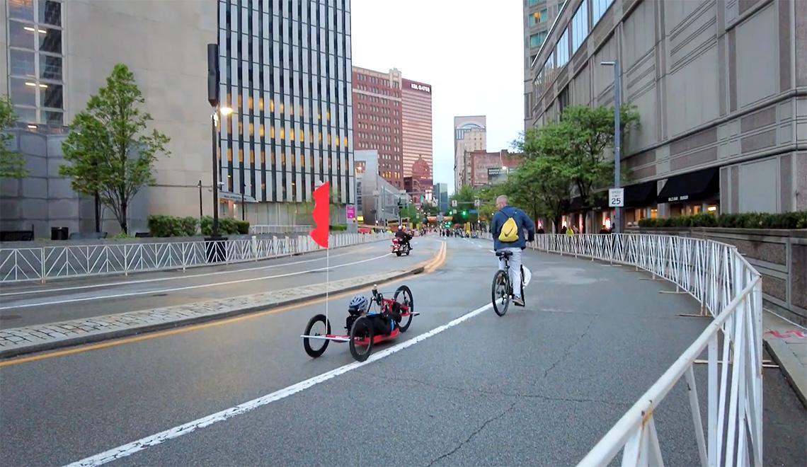 A bicyclist leads a hand cyclist down a street