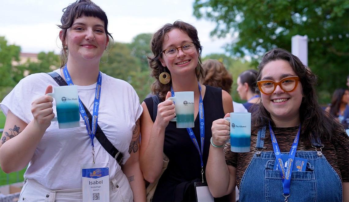 Three people hold up tumblers.